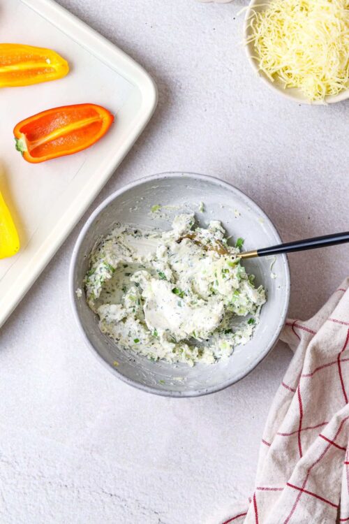 Creamy herb and cheese filling in a mixing bowl for stuffed peppers or baked dishes.