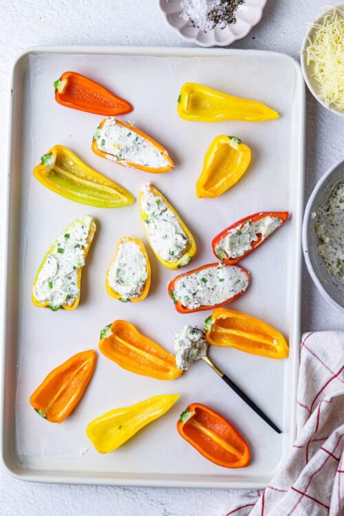 Colorful stuffed bell peppers with creamy cheese filling on baking sheet.