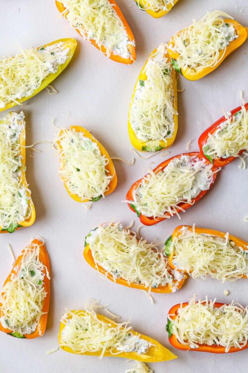 Colorful stuffed bell peppers with shredded cheese and creamy filling ready to bake.