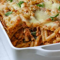 Cheesy baked pasta casserole with melted cheese and fresh basil garnish.