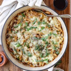 Creamy baked pasta casserole with melted cheese and fresh herbs, served in a rustic dish.