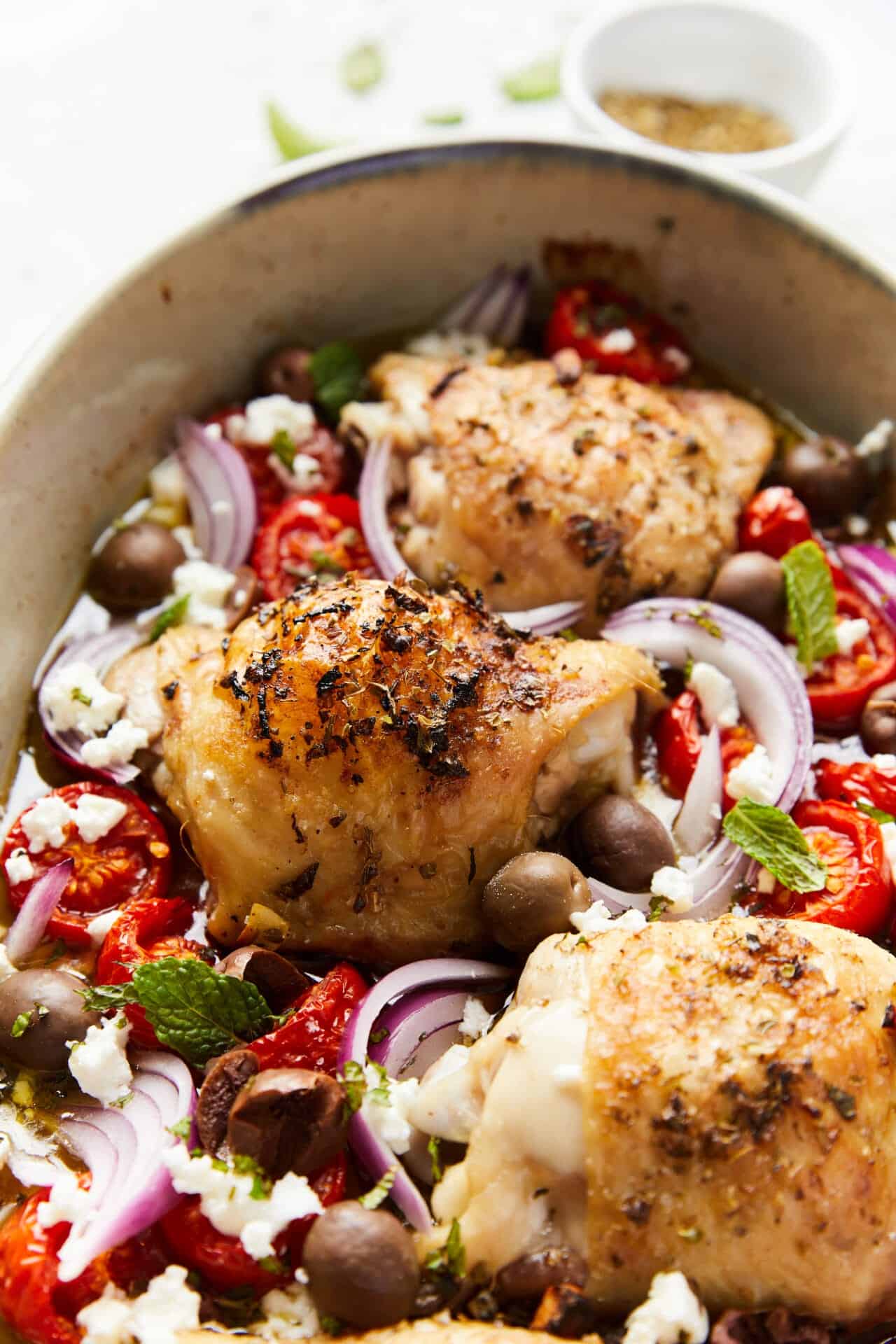 Juicy baked chicken thighs with roasted cherry tomatoes, red onions, black olives, and feta cheese. Perfect for easy weeknight dinners.
