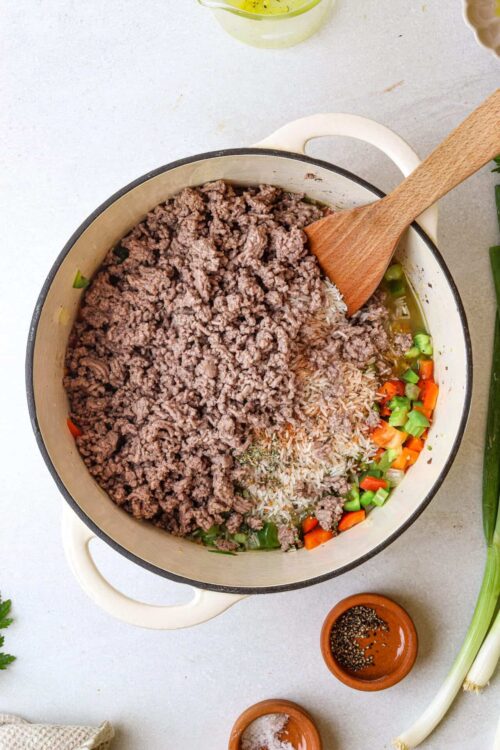 Ground beef cooking in a skillet with vegetables and rice, perfect for homemade recipes.