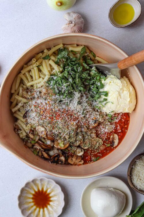 Fresh vegetable pasta salad with herbs, cheese, and a zesty tomato sauce, served in a large bowl.