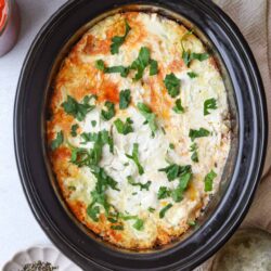 Cheese and herb baked egg casserole in slow cooker, served with fresh parsley.