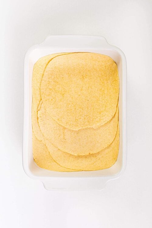 Flour tortillas stacked in a white container for homemade Mexican dishes.