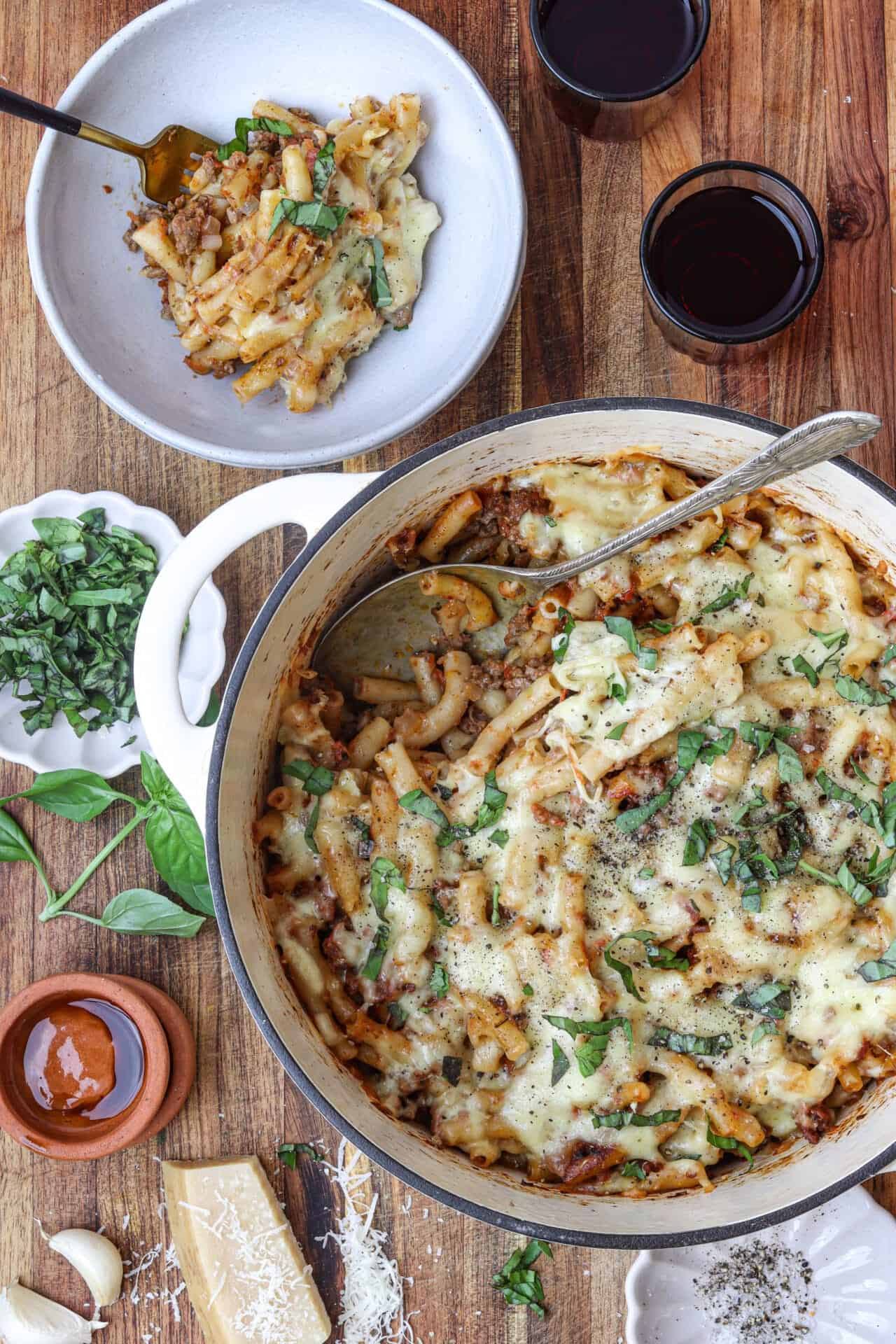 Creamy baked pasta casserole with melted cheese and fresh herbs on a rustic wooden table.