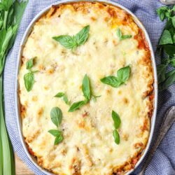 Baked cheesy lasagna in casserole dish with fresh basil.
