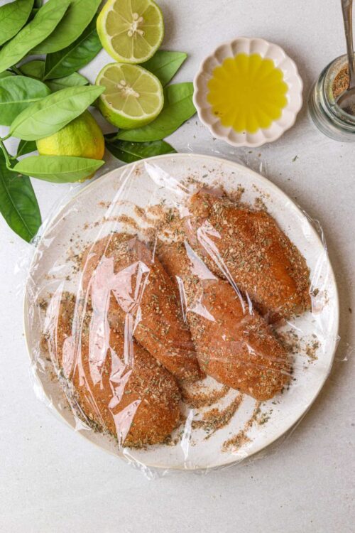 Juicy seasoned chicken breasts marinating with herbs, ready for grilling or baking for a flavorful meal.