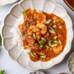 Savory shrimp and sausage gumbo served over rice in a decorative white bowl.