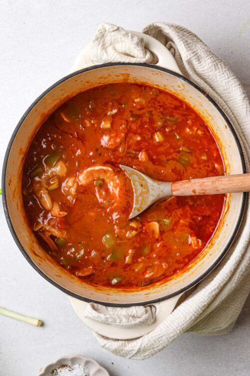 Savory homemade vegetable beef stew in a white enamel pot, close-up view.