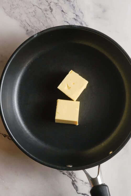 Butter melting in a non-stick frying pan.