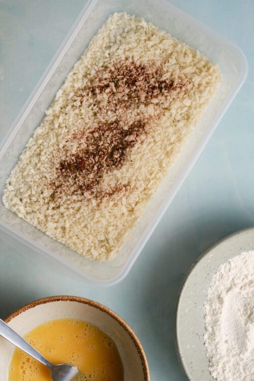 Breadcrumbs with spices and grated cheese in a container, preparation for baking breaded dish.