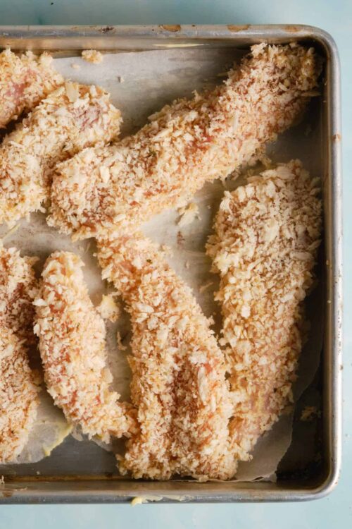 Crispy breaded chicken tenders on a baking sheet.