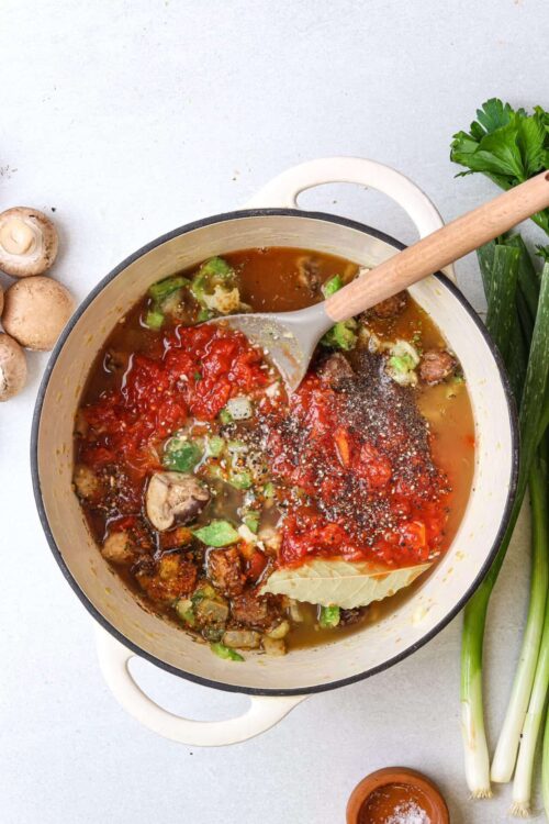 Savory vegetable beef stew simmering in a pot with fresh herbs and spices.