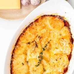 Golden cheesy baked potato casserole topped with melted cheese and fresh herbs.