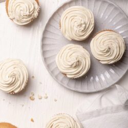 Fluffy vanilla cupcakes with swirled frosting on a gray plate.