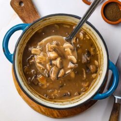 Creamy mushroom soup in a blue pot with salt and pepper shakers on a white surface.