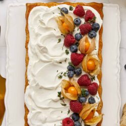 Fresh fruit-topped cake with whipped cream and berries, perfect for dessert or special occasions.