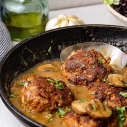Savory meatballs in mushroom gravy in a cast iron skillet.