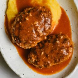 Savory meatloaf with mashed potatoes and rich gravy on a white plate.