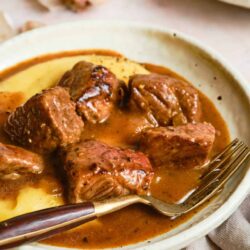 Beef stew with potatoes and rich gravy in a white bowl.