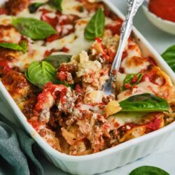 Savory Baked Ziti with ricotta, mozzarella, and fresh basil, served in a white casserole dish.