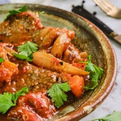 Savory beef and vegetable stew in a rustic ceramic bowl garnished with fresh parsley.