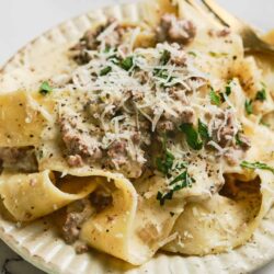 Creamy beef stroganoff served over egg noodles with shredded cheese and chopped parsley.