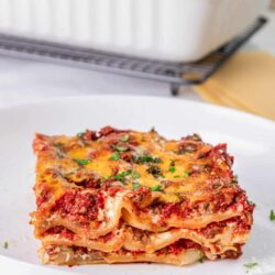 Savory lasagna with cheese and meat on white plate, baked pasta Italian dish, bakedbree.com.