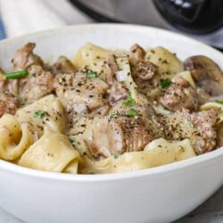 Creamy chicken and pasta casserole with herbs and vegetables in a white dish.