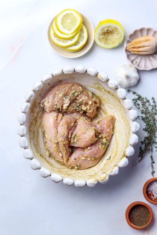 Juice marinating chicken breasts with garlic, herbs, and lemon for flavorful baked chicken.