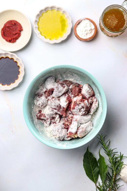 Seasoned raw chicken in a bowl for baking recipes, with herbs and spices.