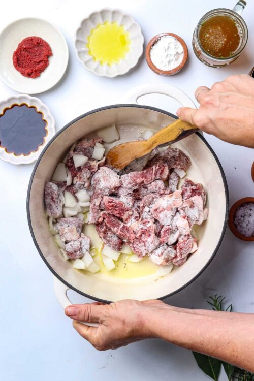 Cooked beef and onions in a cast iron Dutch oven for beef stew recipe.