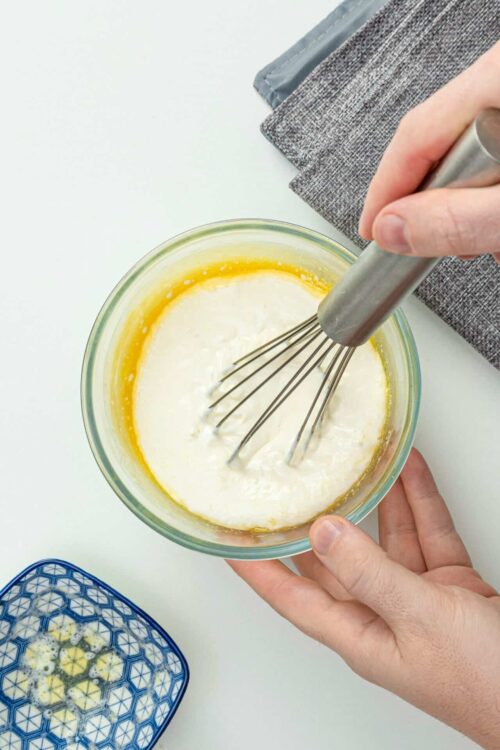 Whisking cream and butter mixture in glass bowl for baking recipes.