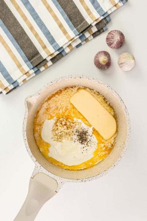 Creamy cheese mixture with garlic and herbs in a speckled pan for baking.