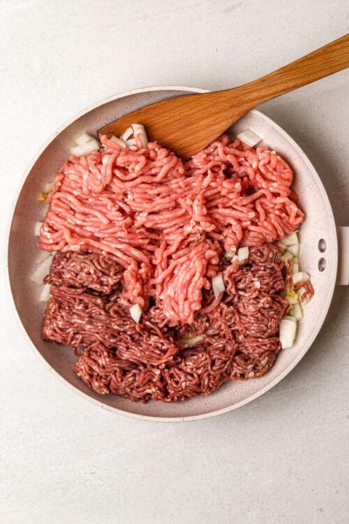 Ground beef and onions cooking in a skillet, preparing for a homemade beef recipe.
