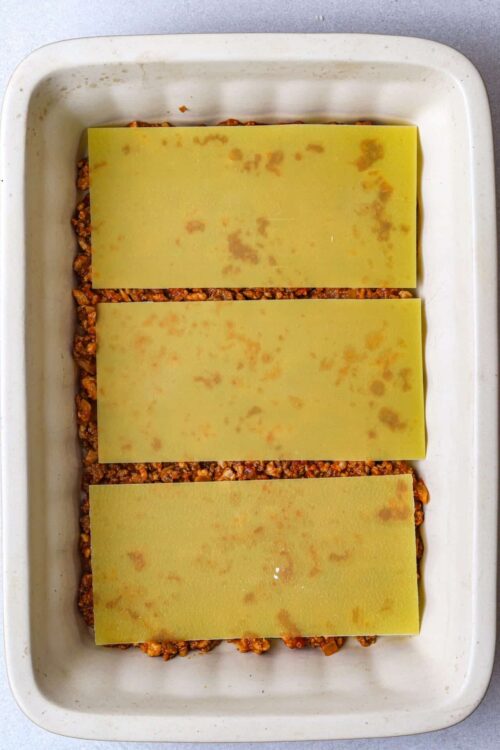 Ground beef taco casserole with three layers of cheese and seasoned beef mixture, baked in a white dish.