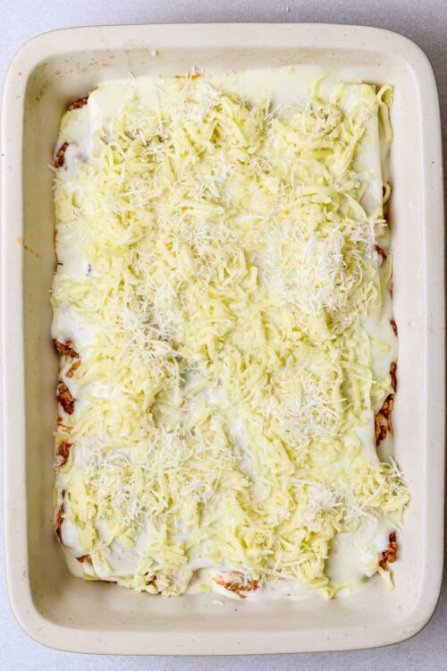 Creamy cheesy baked casserole with shredded cheese on top, ready to bake.