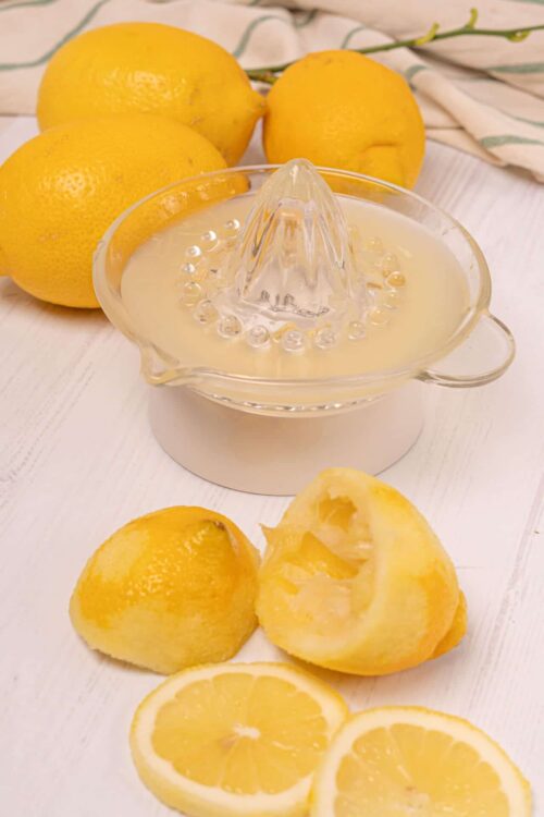 Fresh yellow lemons and a lemon juicer for homemade lemonade or citrus recipes.