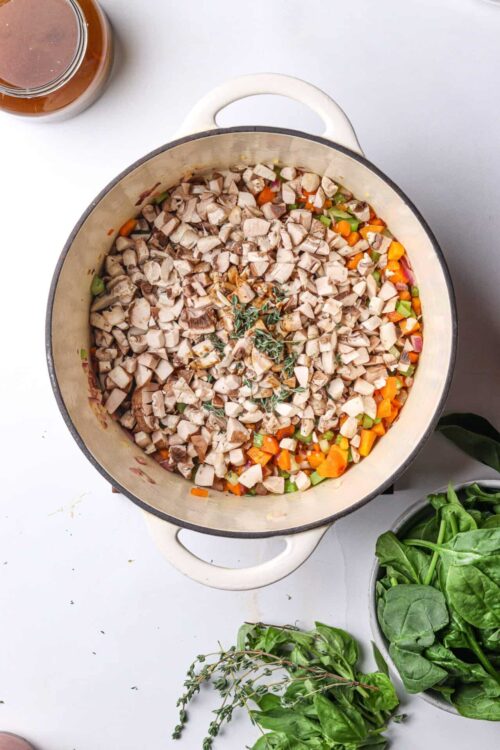 Sautéed vegetables and chicken in a large skillet with herbs, ready for a homemade dinner.
