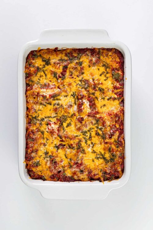 Baked cheesy beef and vegetable casserole in white baking dish.