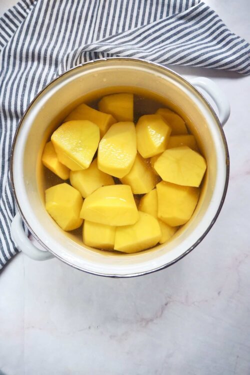 Sweet ripe yellow potatoes soaking in water for cooking or baking.