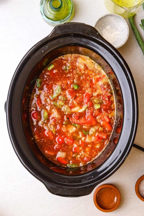 Savory vegetable soup in a slow cooker with diced tomatoes and peppers.