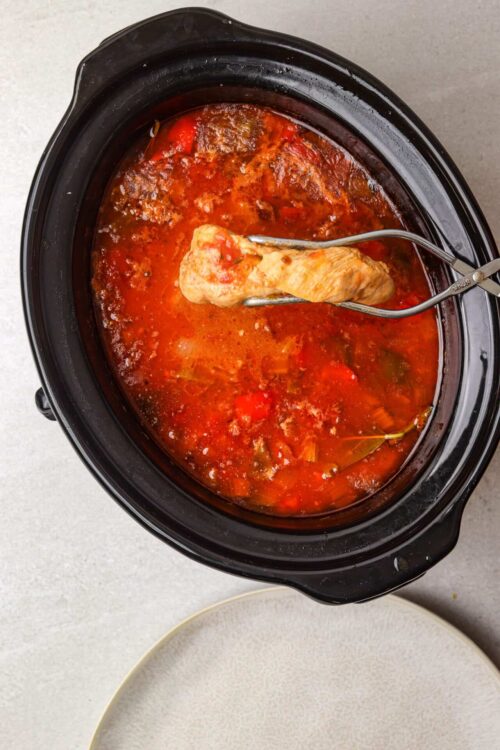 Tender chicken cooking in flavorful tomato sauce in a slow cooker.
