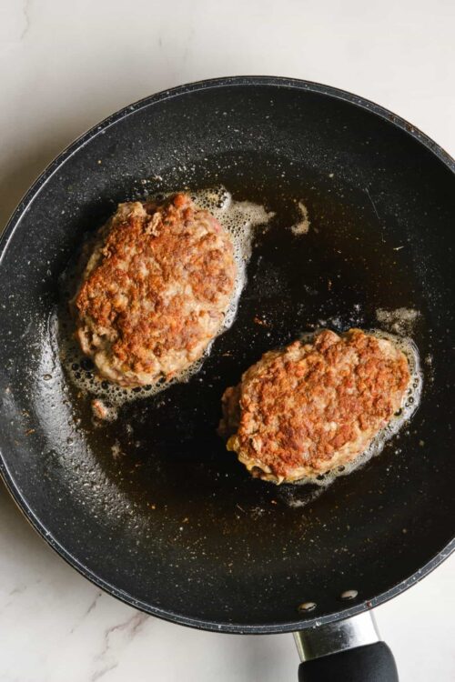 Ground beef patties cooking in a skillet, perfect for homemade burger recipes.