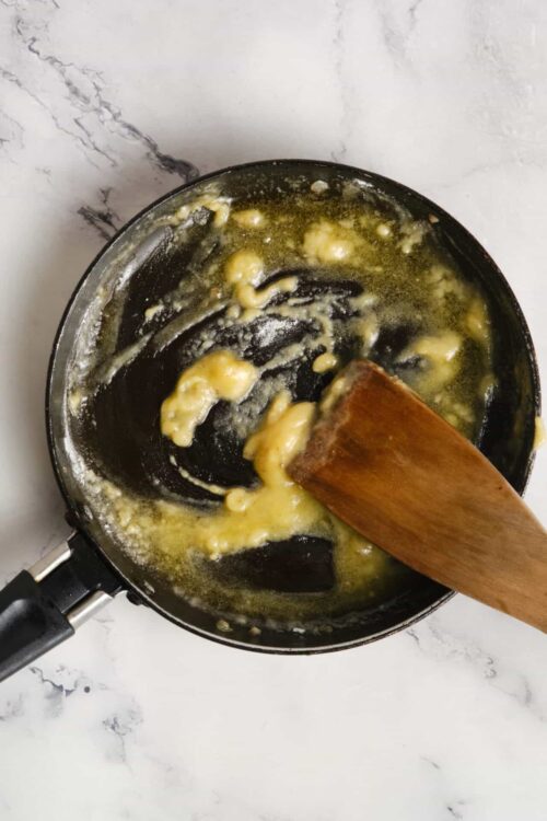 Burnt butter in a frying pan with a wooden spatula for baking or cooking.