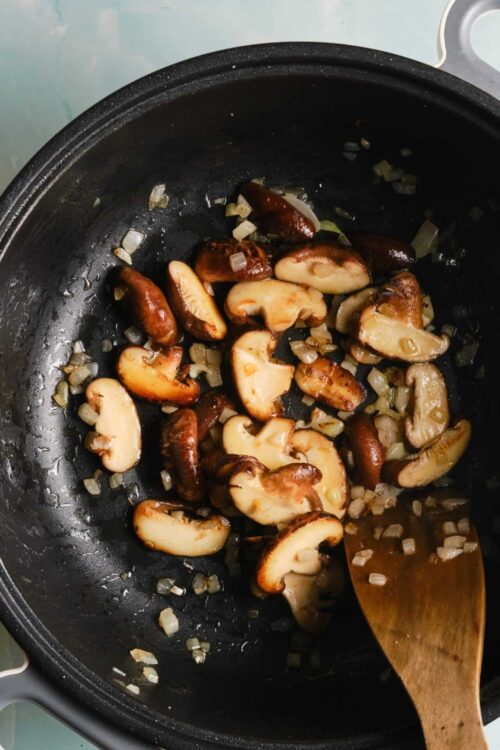 Sautéed mushrooms and onions in a black skillet for cooking or recipe prep.