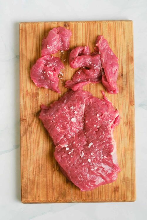 Raw beef steak on a wooden cutting board for cooking or grilling, fresh meat ready to prepare.