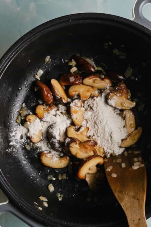 Sautéed mushrooms with onions and flour in a skillet.